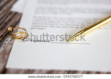 Marriage contract with two golden wedding rings and gold pen, prenuptial agreement, macro close up, sign with signanture,document,agreement concept romance Royalty-Free Stock Photo #1943768377