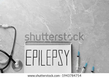 Notebook with word Epilepsy, stethoscope and syringes on grey marble table, flat lay. Space for text