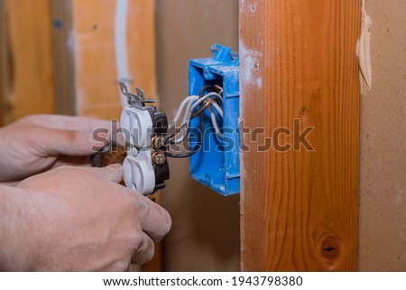 Removal and replacement old broken an electrical outlet into the wall box Royalty-Free Stock Photo #1943798380