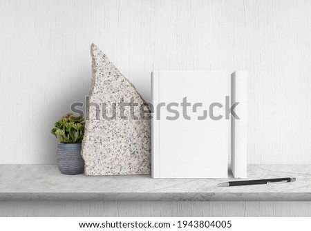 Two hardcover books on concrete counter with flower pots
