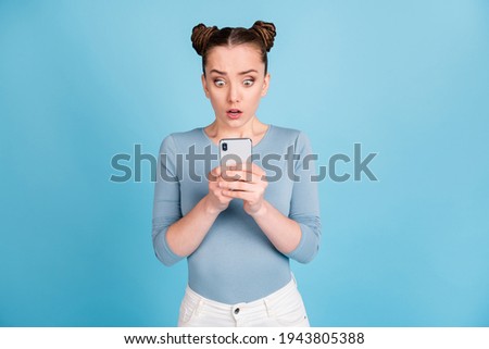 Photo of scared worried young girl post comment mistake hold phone isolated on blue color background