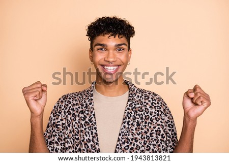 Portrait of brunet hooray guy hands fists wear modern shirt isolated on pastel beige color background