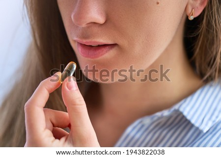 Young woman taking dietary supplement vitamin omega 3 for health. Fish oil softgel, vitamin D and vitamin C for support immunity and disease prevention Royalty-Free Stock Photo #1943822038