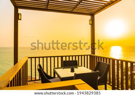 Beautiful outdoor patio with chair table around sea ocean at sunset or sunrise time