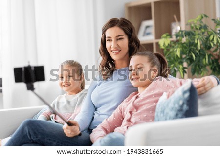 family, technology and people concept - happy mother and daughter with smartphone taking selfie at home