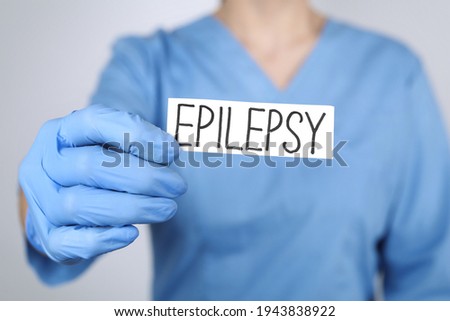 Doctor holding card with word Epilepsy on light grey background, closeup