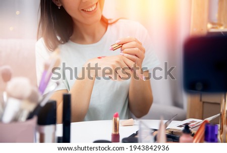 Happy woman vlogger is review cosmetics lipstick recording video stream on phone. Concept Influencer blogger beauty blog.