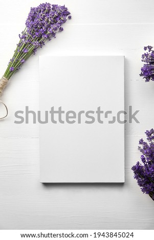 White canvas mockup and lavender flowers bouquet on white wooden table background, flat lay. Blank canvas, top view