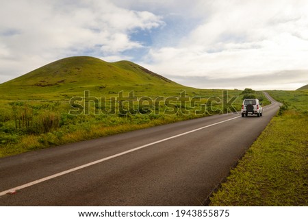 A car through a road in the middle of the countryside of Easter Island, Chile Royalty-Free Stock Photo #1943855875