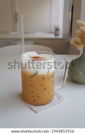 Ice coffee on a wood table with cream being poured into it showing the texture and refreshing look of the drink, with a clean background.
