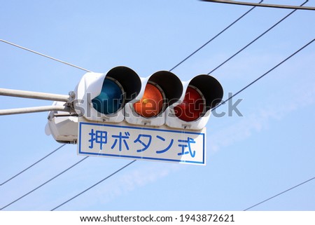 A traffic signal that changes color when pedestrians press a button. Translation: push button.