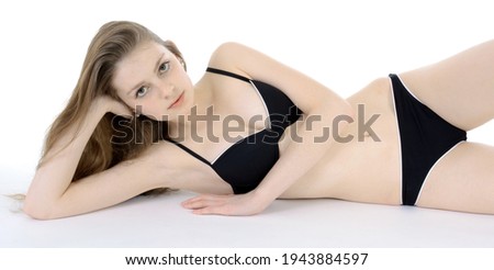 Pretty slim teenage girl wearing a black bikini in studio isolated on white