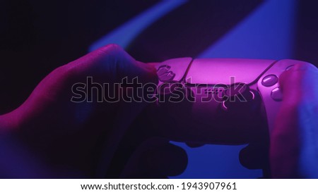 Gamer`s playing a game with a gamepad controller. Game man holding simulator joystick. Close up. Holding simulator joystick. Colorful fashion neon style  Royalty-Free Stock Photo #1943907961