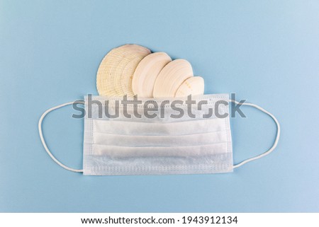 white seashells under a medical mask on a blue background top view