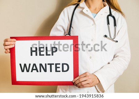 Image of female doctor holding a paper with a text help wanted.