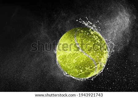 Tennis ball flying in water drops and splashes isolated on black background Royalty-Free Stock Photo #1943921743