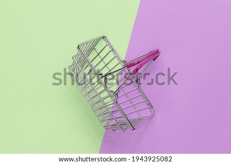 Mini shopping basket on green purple pastel background. Top view