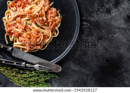Trendy Feta pasta with Oven baked cherry tomatoes and cheese on a plate. Black background. Top view. Copy space