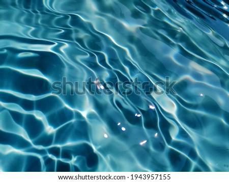 Closeup​ blur​ abstract​ of​ surface​ blue​ water. Abstract​ of​ surface​ blue​ water​ reflected​ with​ sunlight​ for​ background. Blue​ water​ splashed​ use​ for​ graphic​ design.