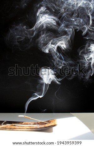 Smoke of insence stick on black vertical background into sun light table meditation yoga practice mindfulness 
