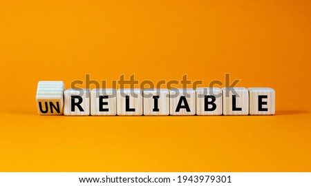 Unreliable or reliable symbol. Turned wooden cubes and changed the word unreliable to reliable. Beautiful orange background, copy space. Business and unreliable or reliable concept. Royalty-Free Stock Photo #1943979301
