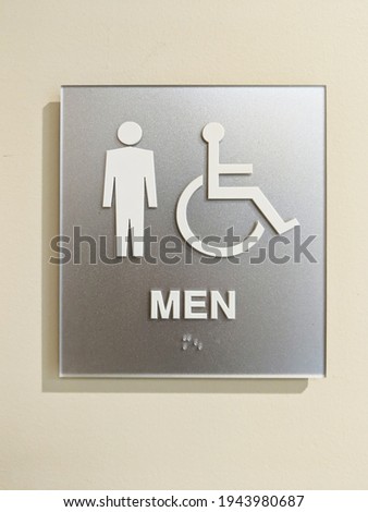 Mens ADA accessible bathroom sign with braille on wall.