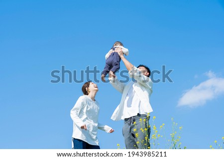 Parents holding their baby high under the blue sky Royalty-Free Stock Photo #1943985211