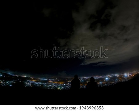 Silhouette of hikers watching the city lights from 'Le Pouce' mountain at night
