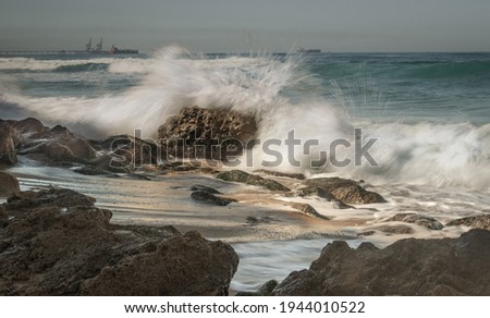 Long exposure image of a wave seascape with rocks against a blue sky. Israel Mediterranean Coast Feb 2021