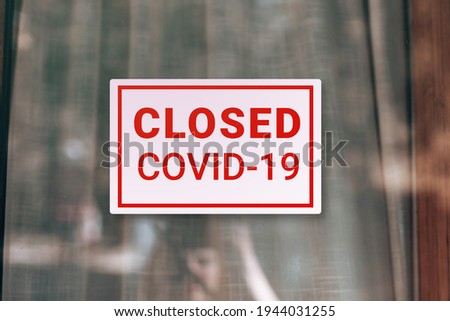 Signboard saying Closed due to Covid-19 at the front door glass. Coronavirus outbreak lockdown