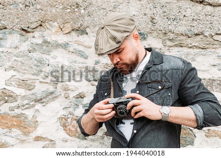 Young hipster man looking at his retro camera. Copy space