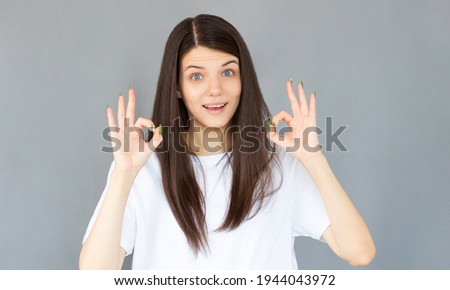Attractive young adult woman showing ok sign. Expression emotion and feelings concept. Studio shot, isolated on gray background