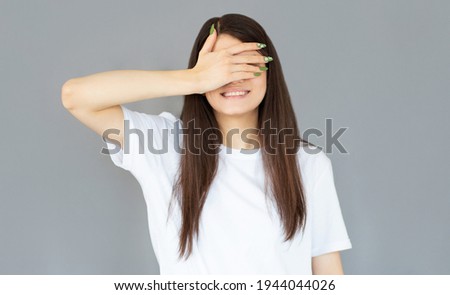 Happy woman closing eyes with hand going to see surprise prepared by boyfriend standing and smiling in anticipation for something wonderful. Young lady covering face with hand
