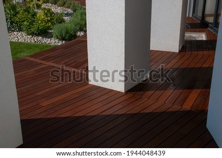 Hardwood Ipe decking, a freshly painted and stained wood deck on the exterior patio of the modern house design Royalty-Free Stock Photo #1944048439