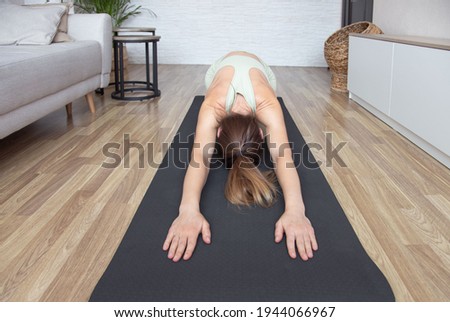 Yoga home stretching meditation woman doing childs pose warm up stretch in living room home. Hands touching floor exercise mat.Fitness relaxation stress- healthy lifestyle concept.