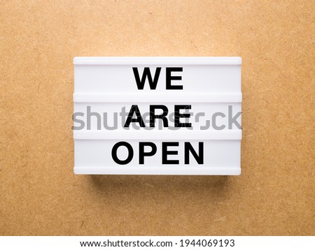 Lightbox with text: we are open on a wooden background.