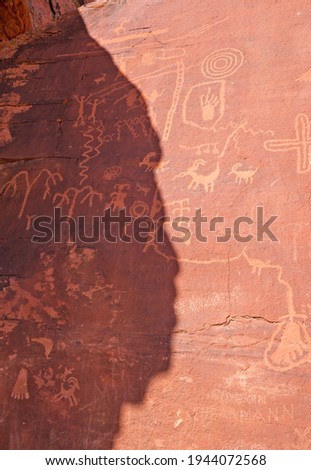 Native American petroglyphs in Nevada with the shadow of a head in profile in summer.