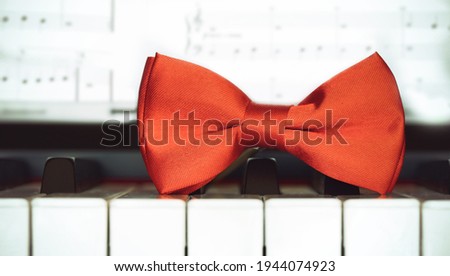 Red bow tie on piano keyboard. Vintage style. Closeup