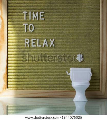 Words TIME TO RELAX. Small toilet in the background. Closeup
