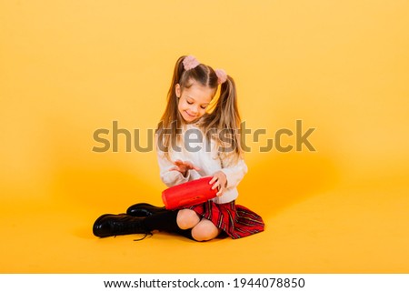Young girl with portable wireless speaker enjoying and dancing on yellow background. Modern fashionable girl listening to music, concept of youth