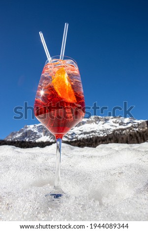 A picture of a glass of Spritz, typical italian aperitif cocktail, on the snow in Cortina D'Ampezzo, Italy