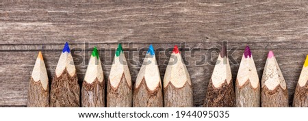 crayons made of real, untreated wood with real tree bark on wooden board in wide panorama format for banner and web design. Horizontal