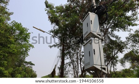 Double NODE cabinet on concrete columns. High speed internet fiber optic connection box with cable reels on low voltage towers on top. On a green tree background with a copy space. Selective focus