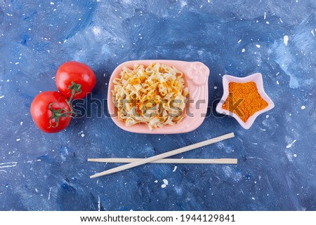 Vintage spaghetti in bowl, tomatoes, chopsticks, turmeric on galaxy blue background. High quality photo