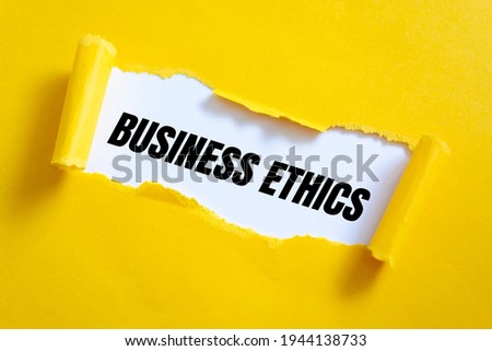 Torn yellow paper on white surface with Business Ethics words.