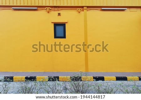 Yellow walls with windows.
Yellow painted wall with green leaf background