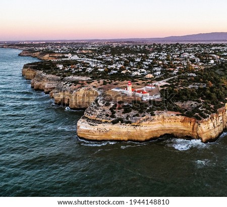 Algarve lighthouse, Aerial drone view of the Farol de Alfanzina, on the coast of Carvoeiro, at sunrise, sunny morning, in Portugal