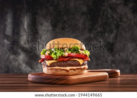 Cheeseburger with tomato and lettuce on wooden board Royalty-Free Stock Photo #1944149665