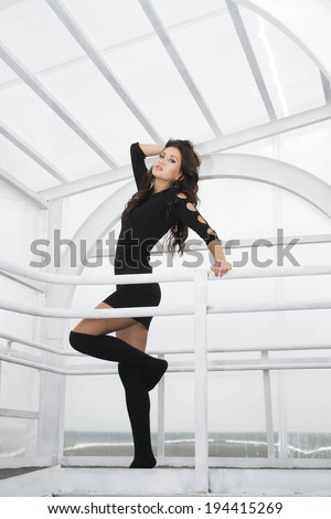 Full length portrait of Young adult latin hispanic girl with long brunette hair dancing in a glass gallery posing in black woolen pantyhose Copy space for inscription