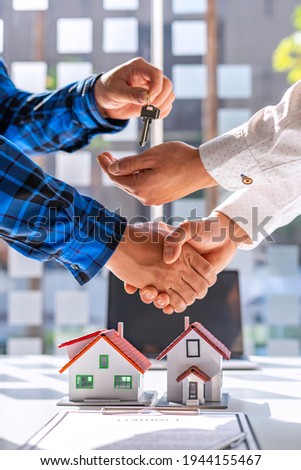 Real estate agents and clients shake hands and deliver the keys. After signing the contract to purchase ownership, the concept mortgage loan is approved.